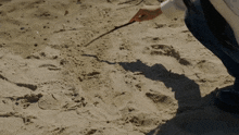 a person holding a wand in the sand on a beach