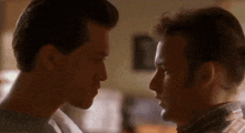 two men are looking into each other 's eyes and kissing .