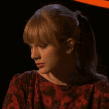 a close up of a woman 's face with a ponytail and a red dress .