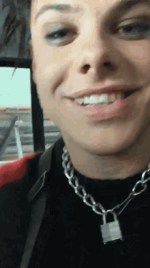 a close up of a person wearing a necklace and smiling