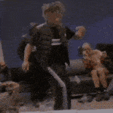 a man in a bear mask is dancing in a room while a woman sits on a couch .
