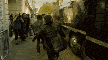 a group of people walking down a street with the letter d on the bottom left