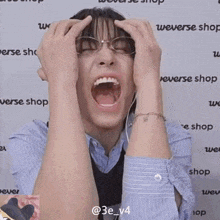 a man with glasses is screaming in front of a wall that says weverse shop