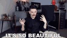 a man with a mustache is sitting in a chair holding a cell phone with the words it 's so beautiful above him