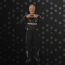 a man wearing a petronas outfit makes a heart shape with his hands