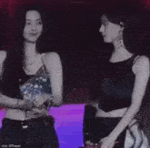two women are standing next to each other and looking at each other in a dark room .