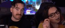 a man and a woman are sitting next to each other in front of a screen that says ultimate .