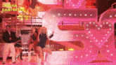 a group of women are dancing in front of a large pink letter s.