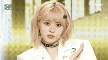a blonde woman wearing a choker and a white jacket is making a face