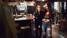 two women are standing next to each other in a room in a restaurant .