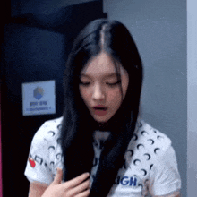 a young woman with long black hair is standing in front of a door .