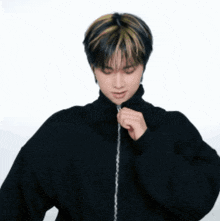 a young man wearing a black sweater with a chain around his neck