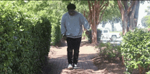 a man in a grey sweater is walking down a path