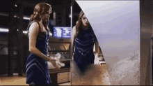 a woman in a blue dress is standing in front of a mirror looking at her reflection .