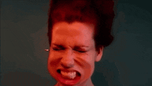 a woman with red hair is making a funny face with her eyes closed and her mouth open .