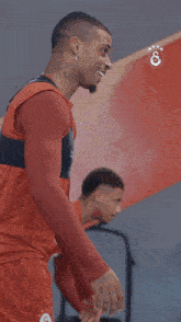 a man wearing a red tank top that says caftan on it