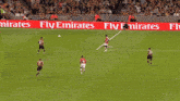 soccer players on a field with emirates fly emirates banners