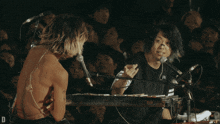 a man singing into a microphone while another man looks on