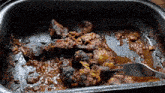 a pan filled with meat and sauce with a fork sticking out of it