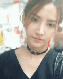a close up of a woman wearing a choker and a black shirt .