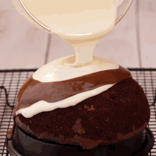a chocolate cake with white frosting and chocolate icing being poured on it
