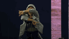 a man wearing a striped jacket and a bandana is dancing on stage