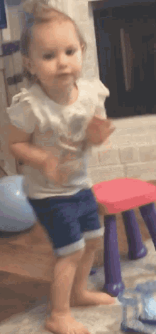 a little girl in a white shirt and blue shorts is dancing