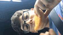 a young boy wearing glasses is eating something