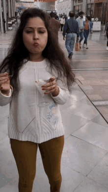 a woman in a white sweater is holding a glass of wine