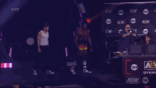 a wrestler is standing in front of a wall that says aew on it