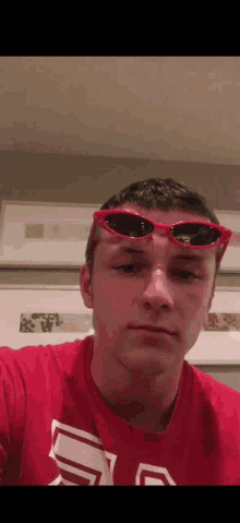 a man wearing red sunglasses and a red shirt with the letter a on it