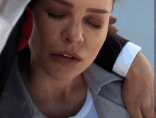 a close up of a woman 's face with a man 's arm around her shoulder