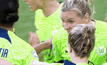a group of women are hugging each other on a soccer field .