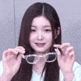 a young woman is holding a pair of clear glasses in her hands .