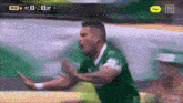 a soccer player in a green jersey is celebrating a goal with a yellow sign that says free
