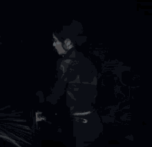 a woman in a black jacket is standing in the dark .