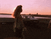 a woman in a green tank top is walking in front of a car