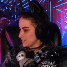 a woman is sitting in a chair wearing headphones and holding a stuffed animal .