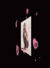 a picture of a man squatting on a beach with pink hearts around him