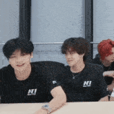 a group of young men are sitting at a table with one wearing a shirt that says ni on it