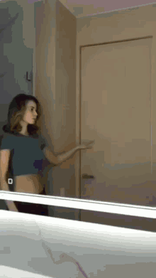 a woman is standing in front of a mirror looking at herself