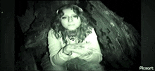 a woman is sitting in front of a tree in a dark room .