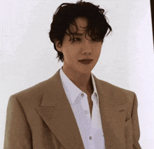 a man wearing a brown jacket and white shirt