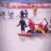 a group of people are rowing boats in the water and one of them is wearing a red shirt that says ' a '
