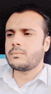a man with a beard and a white shirt is looking at the camera