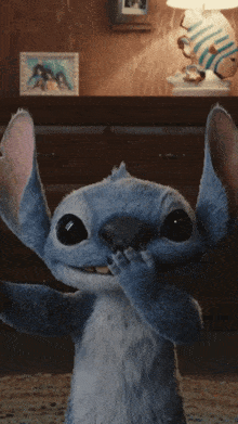 a stuffed animal that looks like stitch is covering his face