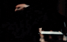 a close up of a man 's face in a dark room with a blurred background .