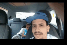 a man in a blue hat is sitting in the back seat of a car with a baby