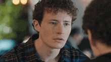 a man with curly hair is sitting at a table with another man .