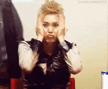 a woman is making a funny face with her hands on her head .